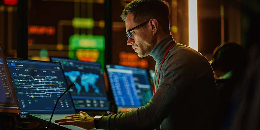 Man looking at computer screens displaying network status information